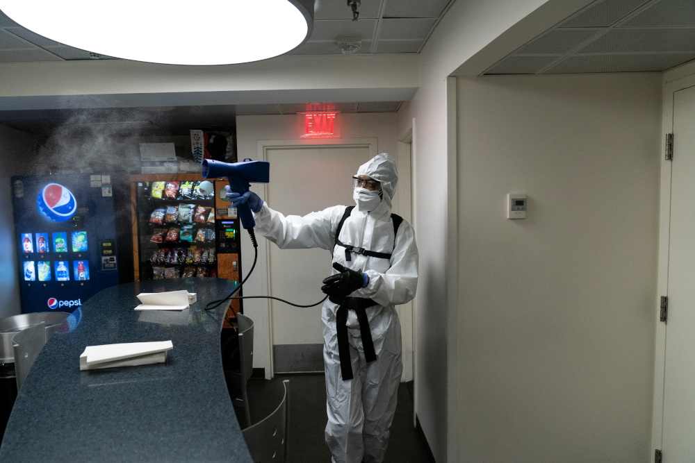 A member of the cleaning staff sprays press areas of the White House, Monday, Oct. 5, 2020, in Washington. (AP Photo/Alex Brandon)