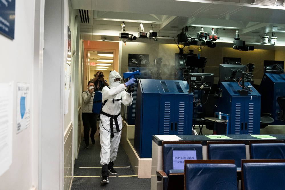 A member of the cleaning staff wears a protective suit as she sprays The James Brady Briefing Room of the White House, Monday, Oct. 5, 2020, in Washington. (AP Photo/Alex Brandon)