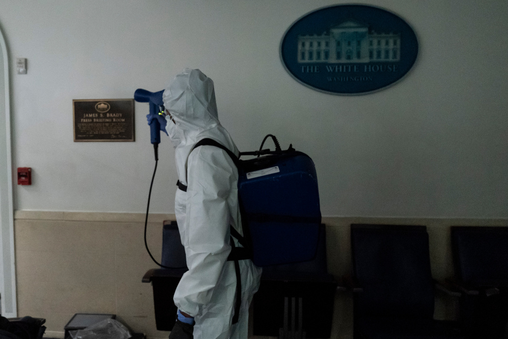 A member of the cleaning staff dressed in a protective suit, sprays the James Brady Briefing Room of the White House, Monday, Oct. 5, 2020, in Washington. (AP Photo/Alex Brandon)