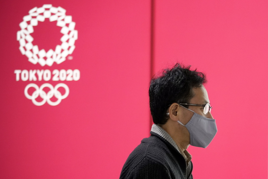 epa08815240 A passerby wearing a protective mask walks past a postponed Tokyo Olympic Games advertising board in Tokyo, Japan, 12 November 2020. According to latest media reports, the Japanese government and the Games Organizing Committee are considering measures to exempt foreign visitors from a 14-day quarantine requirement after entering Japan if certain conditions are met. The final decision will be made by next spring. The announcement came as Japan recorded its highest daily coronavirus infection numbers with more than 1,600 cases nationwide.  EPA/FRANCK ROBICHON