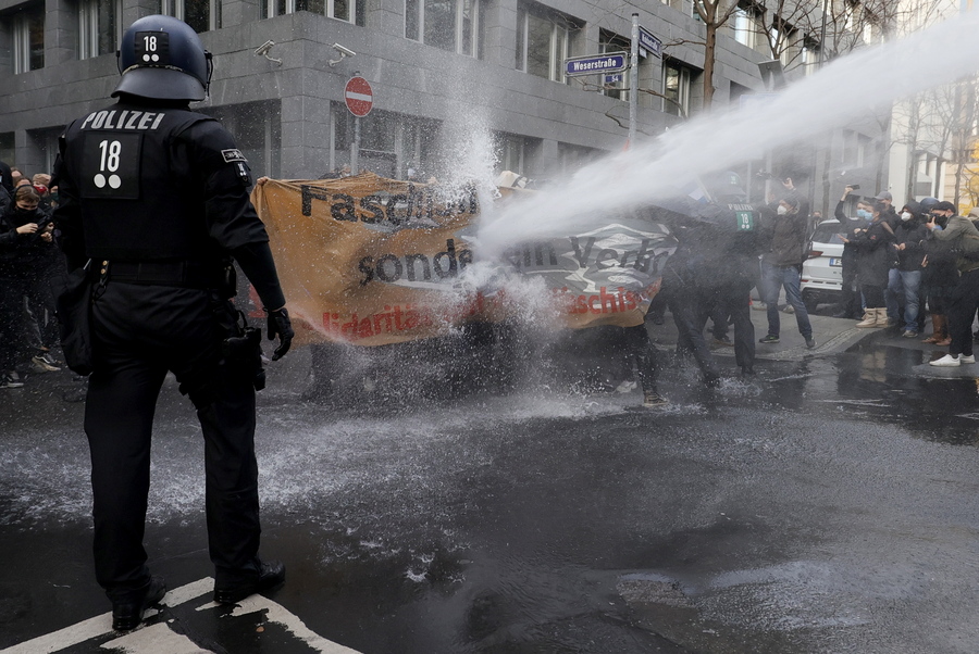 epa08819898 A police water cannon fires against left-wing protesters who try to stop a demonstration against the coronavirus restrictions, in Frankfurt am Main, Germany, 14 November 2020. The protests organized by the Third Position movement 'Querdenken' were held against government-imposed semi-lockdown measures aimed at curbing the spread of the coronavirus pandemic. Starting 02 November, all restaurants, bars, cultural venues, fitness studious, cinemas and sports halls will be forced to close for four weeks as a lockdown measure to rein in skyrocketing coronavirus infection rates. EPA/RONALD WITTEK