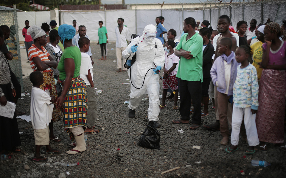 FILE - In this Tuesday, Sept. 30, 2014, file photo a  medical worker sprays people being discharged from the Island Clinic Ebola treatment center in Monrovia, Liberia. Ebola has killed more than 4,500 people in West Africa and wreaked havoc on the region, but some Africans see a bright side: The virus has been limited to five countries. It has even been beaten back in two of those countries. (AP Photo/Jerome Delay, File)