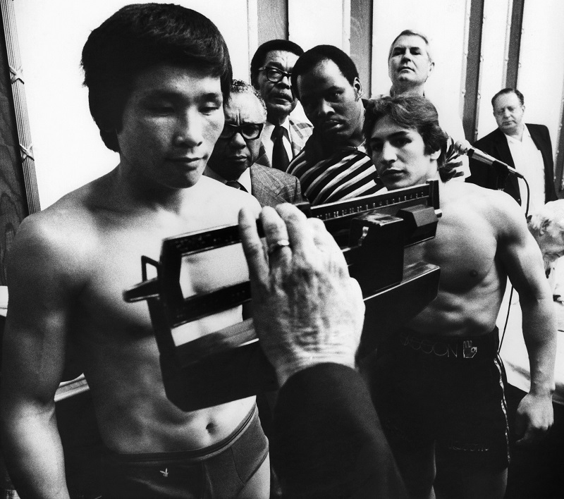 WBA Lightweight champion Ray "Boom Boom" Mancini, right, watches as challenger Duo Koo Kim of Korea stands on the scale during the weigh-in for their championship fight in Las Vegas on Nov. 12, 1982. (AP Photo/Scott Henry)