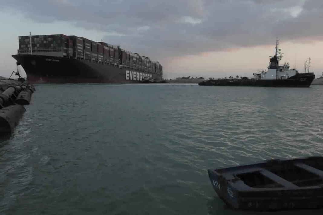 In this photo released by the Suez Canal Authority, tug boats work to free the Panama-flagged, Japanese-owned Ever Given, which is lodged across the Suez Canal, Sunday, March 28, 2021. Two additional tugboats are speeding to canal to aid efforts to free the skyscraper-sized container ship wedged for days across the crucial waterway. That's even as major shippers increasingly divert their boats out of fear the vessel may take even longer to free. (Suez Canal Authority via AP)