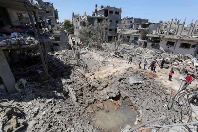 Palestinians gather at the site of destroyed houses in the aftermath of Israeli air and artillery strikes as cross-border violence between the Israeli military and Palestinian militants continues, in the northern Gaza Strip May 14, 2021. REUTERS/Mohammed Salem     TPX IMAGES OF THE DAY