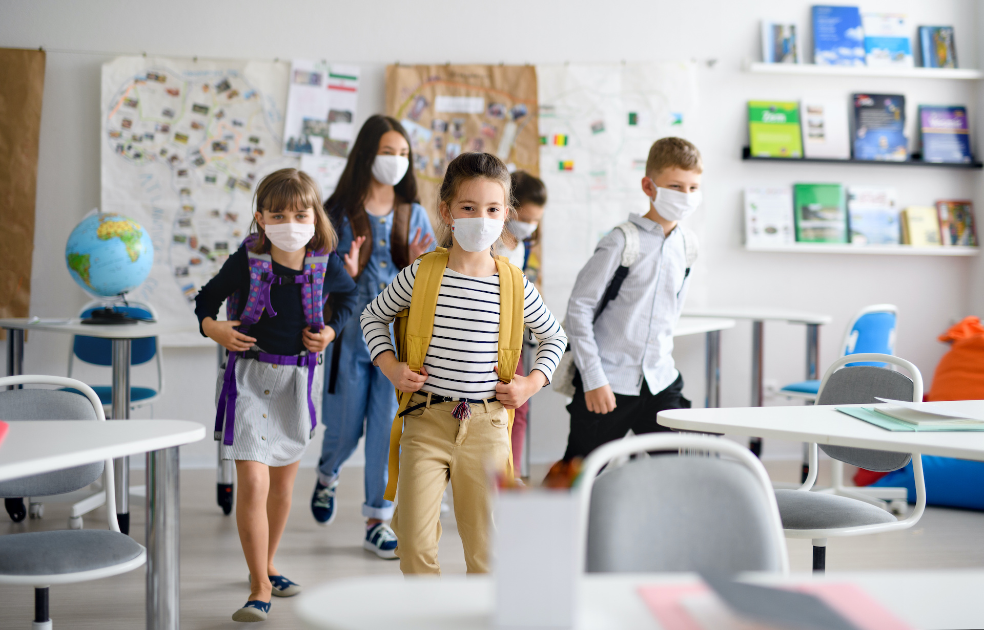 Group of children with face mask back at school after covid-19 quarantine and lockdown, entering classroom.