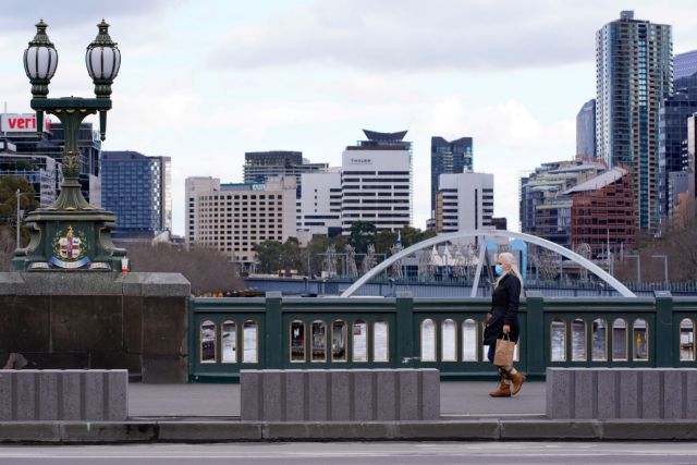 FILE PHOTO: A lone woman, wearing a protective face mask, walks across a city centre bridge as the state of Victoria looks to curb the spread of a coronavirus disease (COVID-19) outbreak in Melbourne, Australia, July 16, 2021.  REUTERS/Sandra Sanders/File Photo