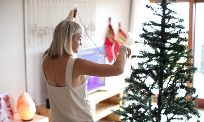 A young woman setting up a Christmas tree at their home in Gordon's Bay, South Africa.