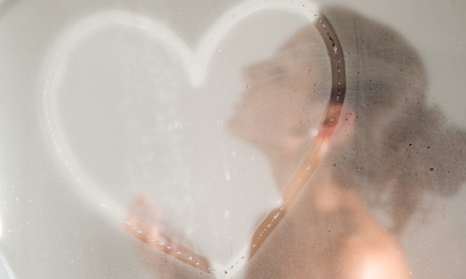 Beautiful girl showering with a drawn heart on the steamy shower glass door. Converted from RAW.