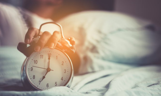 Clock on the bed in the morning.