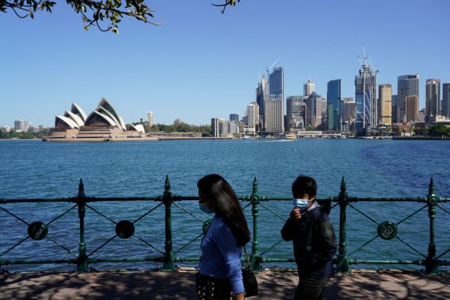 FILE PHOTO: People in protective face masks walk along the harbour waterfront across from the Sydney Opera House during a lockdown to curb the spread of  coronavirus disease (COVID-19) outbreak in Sydney, Australia, October 6, 2021. REUTERS/Loren Elliott/File Photo