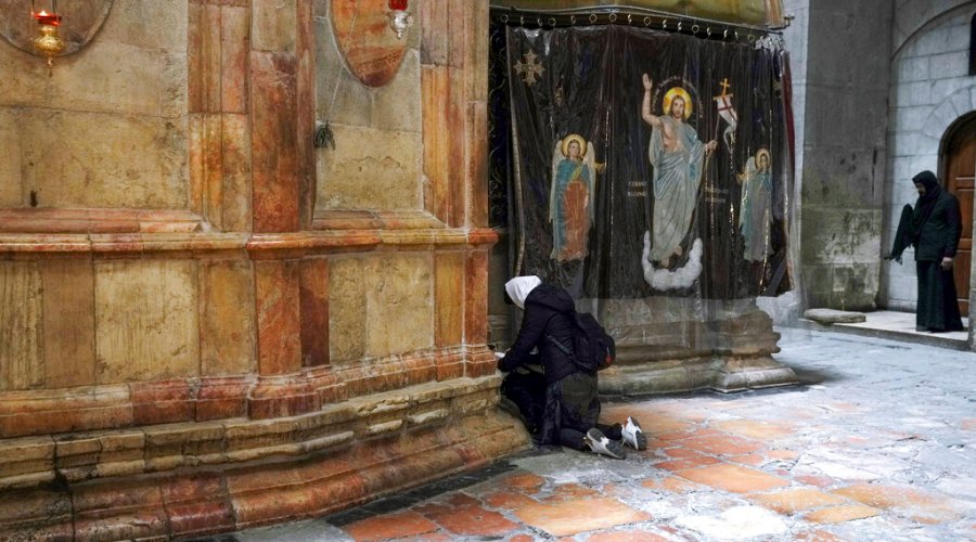 A woman pray at the Church of the Holy Sepulchre, where many Christians believe Jesus was crucified, buried and rose from the dead, in the Old City of Jerusalem, Thursday, March 17, 2022. The three Christian communities that have uneasily shared their holiest site for centuries are embarking on a project to restore the ancient stone floor of the Jerusalem basilica. The project includes an excavation that could shed light on the rich history of the Church of the Holy Sepulchre in the Old City. (AP Photo/Mahmoud Illean)