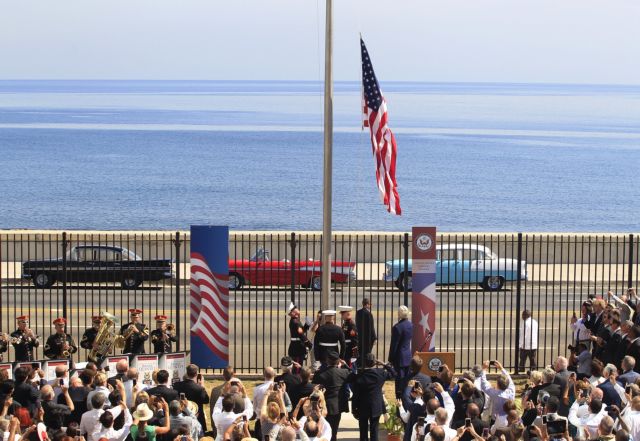 U.S. marines raise the U.S. flag while watched over by U.S. Secretary of State John Kerry (C, at lectern, back to camera) at the U.S. embassy in Havana, Cuba, August 14, 2015. U.S. Marines raised the American flag at the embassy in Cuba for the first time in 54 years on Friday, symbolically ushering in an era of renewed diplomatic relations between the two Cold War-era foes.  REUTERS/Stringer