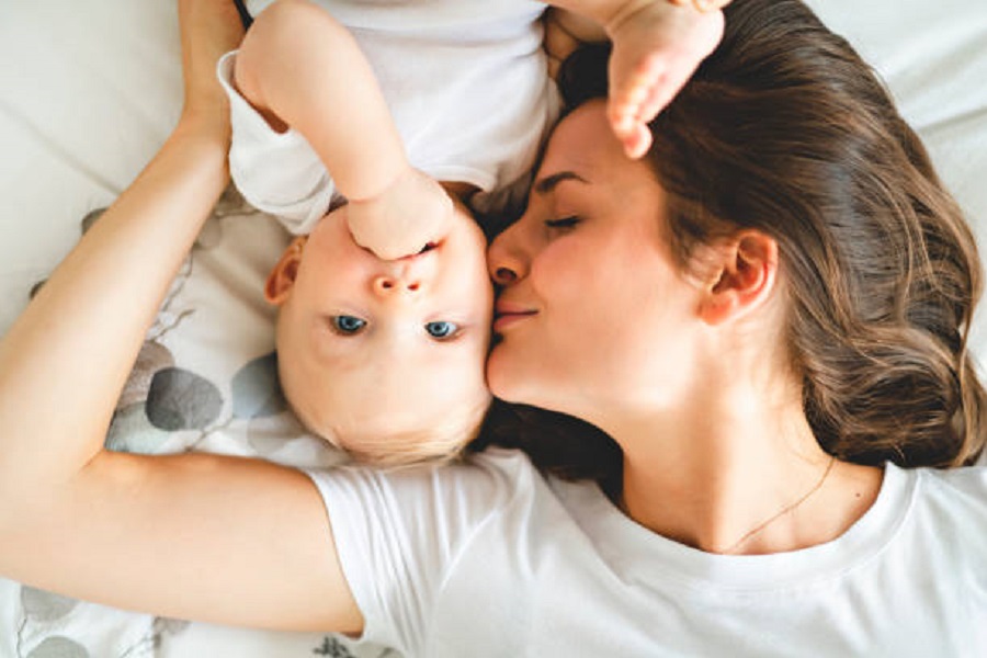 A happy mother with baby on bed