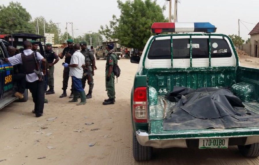 A covered-up dead body lies in the trunk of a police vehicle as members of security forces stand near the site of a suspected Boko Haram attack on the edge of Maiduguri's inner city, Nigeria April 2, 2018. REUTERS/Ahmed Kingimi