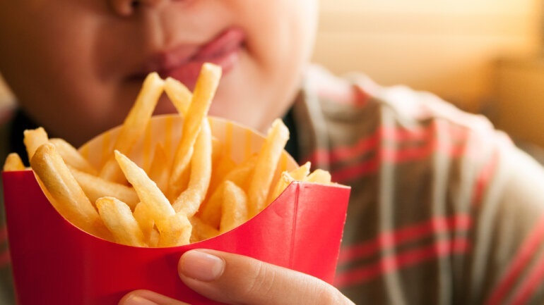 Closeup of kid holding french fries packet