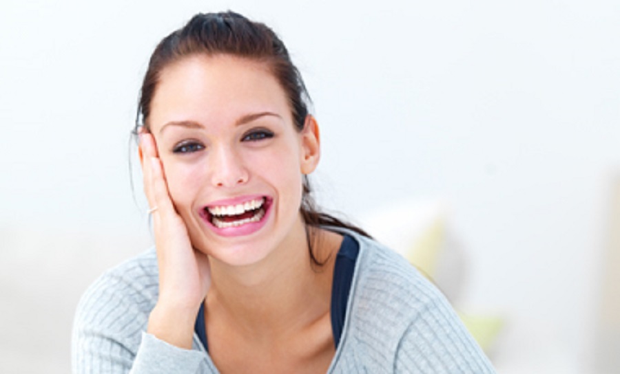 Closeup portrait of a happy young woman laughing sitting with hand on desk