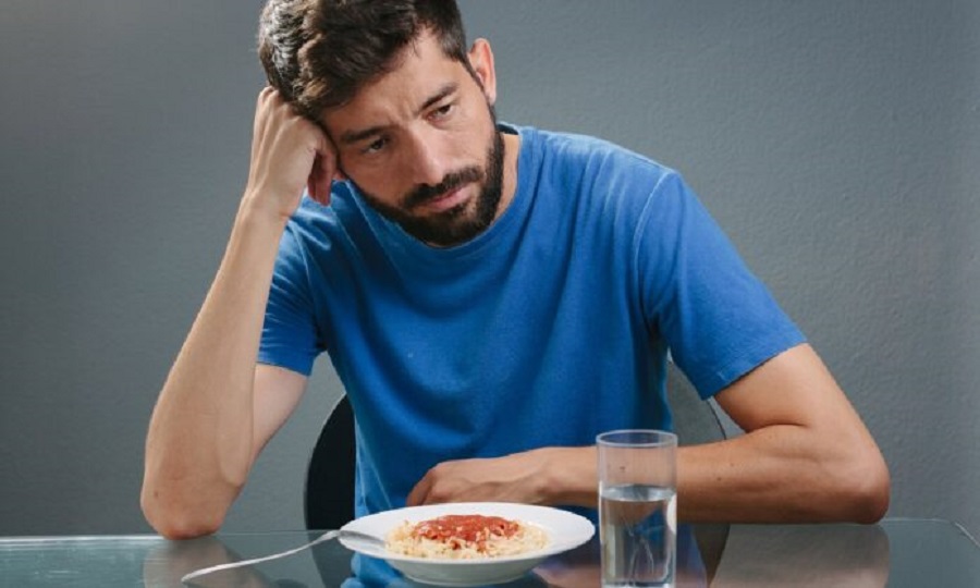 Portrait of man with no appetite in front of the meal. Concept of loss of appetite; Shutterstock ID 520761115