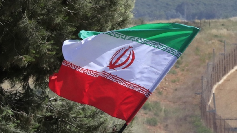 A Hezbollah supporter marking "Liberation Day", the 23rd anniversary of Israel's withdrawal from southern Lebanon in May 25, 2000, waves an Iranian flag in front of a passing Israeli armored vehicle, on the Lebanese-Israeli border in the southern village of Kfar Kila, Thursday, May 25, 2023. (AP Photo/Mohammed Zaatari)