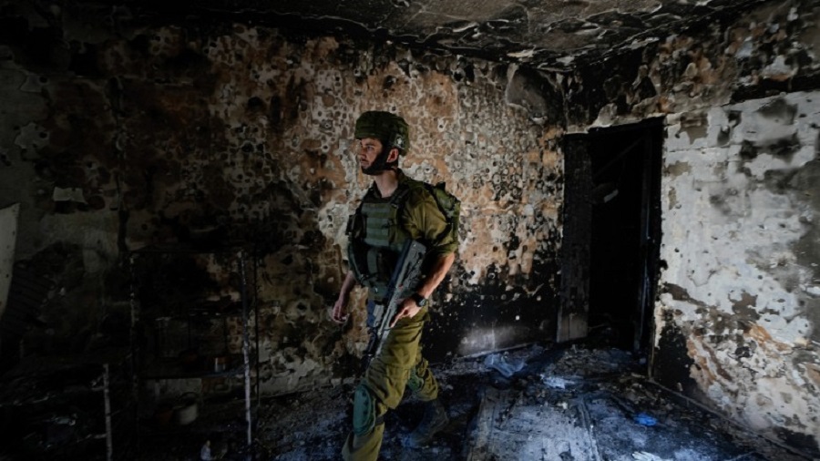 An Israeli soldier inspects a house damaged by Hamas militants in Kibbutz Kfar Azza, Israel, Wednesday, Oct. 18, 2023. The Kibbutz was overrun by Hamas militants from the nearby Gaza Strip on Oct. 7, when they killed and captured many Israelis. (AP Photo/Ariel Schalit)