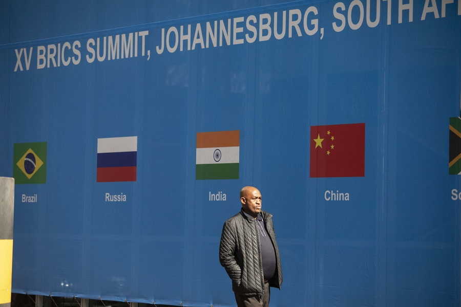 epa10809139 A man walks past a banner as final preparations are underway for the 15th BRICS Summit at the Sandton Convention Centre, Johannesburg, South Africa, 20 August 2023. South Africa is hosting the 15th BRICS Summit starting 22 August, where emerging economies of Brazil, Russia, India, South Africa and China will get together. The Russian president will not attend the summit.  EPA/KIM LUDBROOK