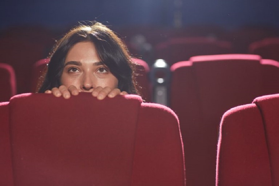 portrait-scared-young-woman-hiding-seat-while-watching-horror-movie-empty-cinema-hall-copy-space-