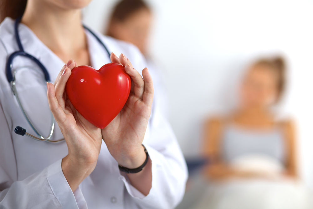 Young,Woman,Doctor,Holding,A,Red,Heart,,Isolated,On,White