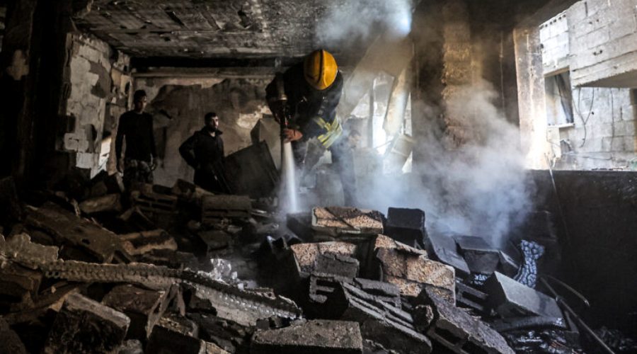 A Palestinian civil defence member sprays water with a firehose in a building damaged by fire in the Nur Shams camp for Palestinian refugees near the northern city of Tulkarm in the occupied West Bank on December 26, 2023 in the aftermath of an Israeli raid. (Photo by Zain JAAFAR / AFP)