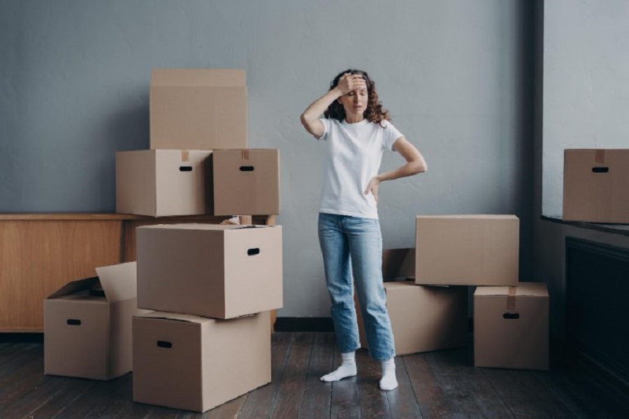 tired-upset-woman-standing-with-cardboard-boxes-empty-room-eviction-divorce-hard-moving-day-