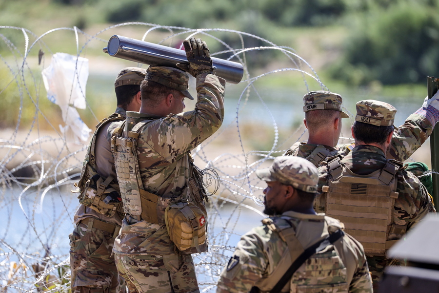 epa10875846 Texas National Guard members fix the concertina wire near the Rio Grande in Eagle Pass, Texas, USA, 21 September 2023. The Mayor of Eagle Pass, Rolando Salinas Jr. on 19 September declared a 'local state of disaster' in an emergency declaration issued after over a thousand migrants had crossed the border. About 3,000 migrants crossed into Eagle Pass on 20 September and another 3,000 are on track to enter on 21 September, according to the U.S. Representative Tony Gonzales.  EPA/ADAM DAVIS