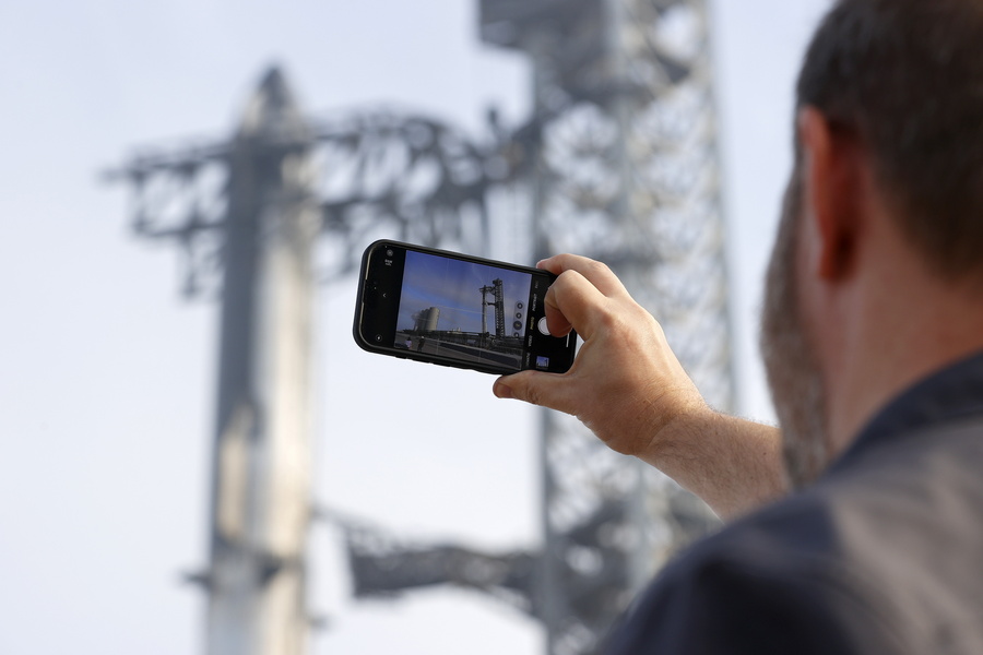 epa11219418 An onlooker takes a photo of the mega rocket Starship, which wis put in position before a test launch as SpaceX gets ready for their upcoming launch at Starbase in Boca Chica, Texas, USA, 13 March 2024. This will be the third attempt to test the mega rocket Starship.  EPA/ADAM DAVIS