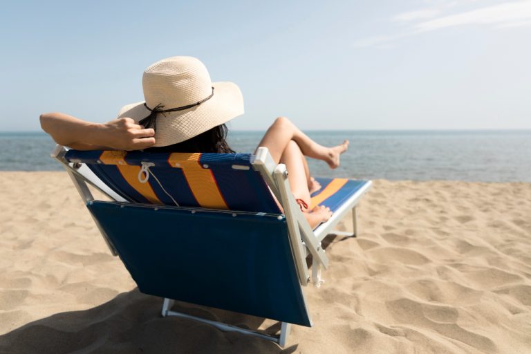 back-view-woman-sitting-beach-chair-looking-sea