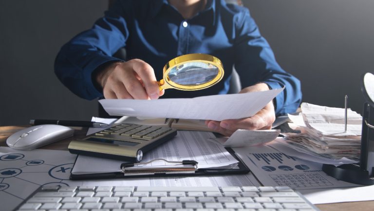 businessman-holding-magnifying-glass-with-documents