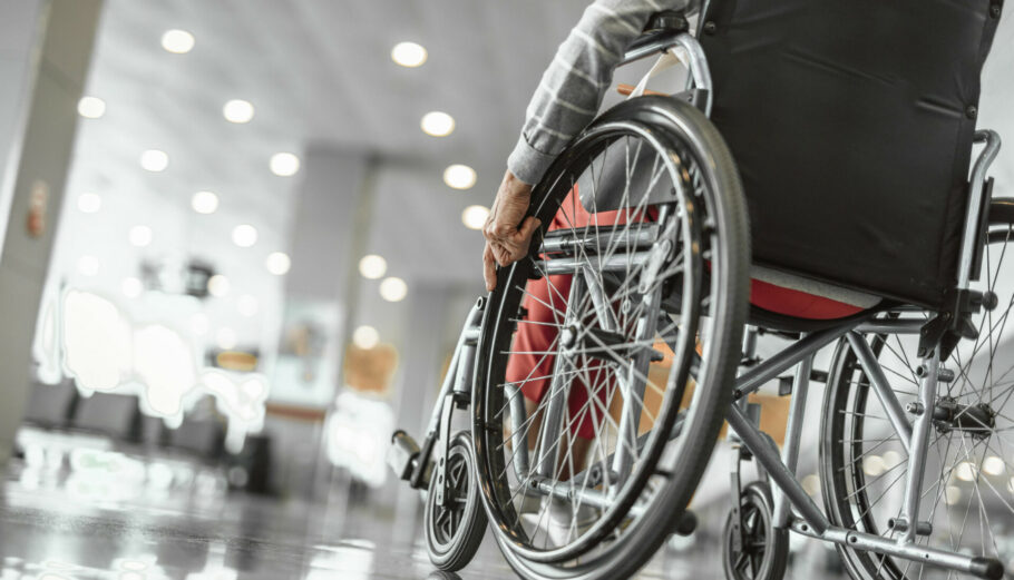 Cropped photo of mature female on wheelchair in the lobby at airport hall. Copy space in left side