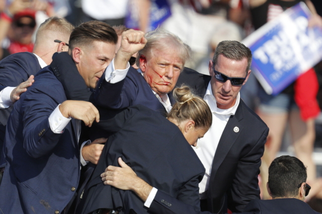 epa11476882 Former US President Donald Trump is rushed off stage by secret service after an incident during a campaign rally at the Butler Farm Show Inc. in Butler, Pennsylvania, USA, 13 July 2024. Former US President Donald Trump stated on social media that a bullet pierced the upper part of his right ear and that a person attending the rally was killed, another was injured and that the alleged shooter was dead.  EPA/DAVID MAXWELL