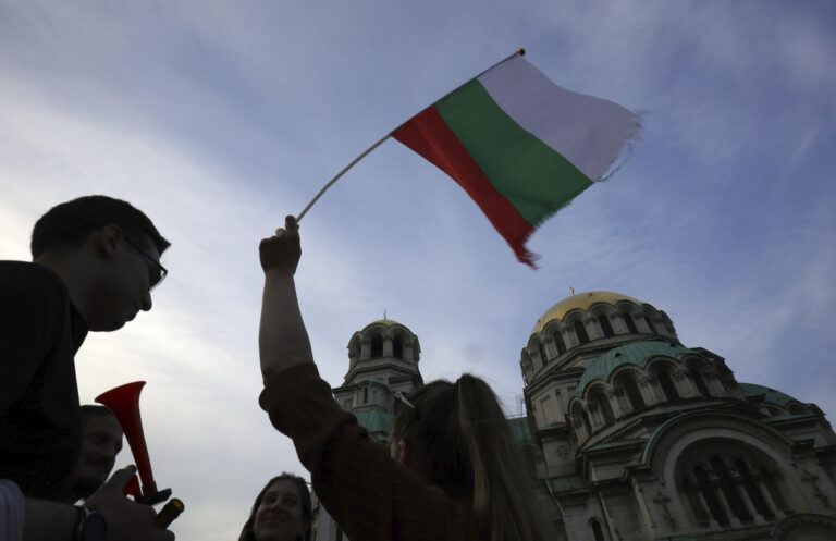 FILE - A pro-government protester holds a Bulgarian flag during a demonstration in support of incumbent Bulgarian government near the Bulgarian Parliament building in Sofia, Tuesday, June 21, 2022. Bulgaria’s parliament on Tuesday formally approved an interim government to run the EU member country until snap parliamentary and regular European Parliament elections on June 9, 2024. (AP Photo/Valentina Petrova, File)