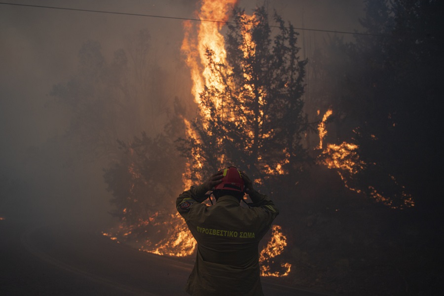 A firefighter adjusts his helmet in Varnava village during a wildfire, north of Athens, Greece, Sunday, Aug. 11, 2024, with many regions of the country on high alert due to high temperatures and wind speeds. (AP Photo/Michael Varaklas)