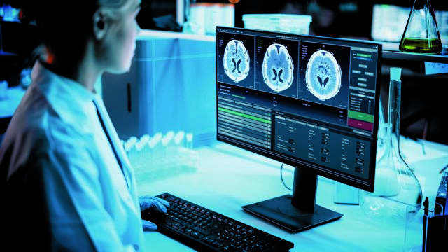 Medical Research Laboratory: Portrait of Female Scientist Working on Computer Showing MRI Brain Scans. Advanced Scientific Lab for Medicine, Cancer Development. Dark Blue Shot