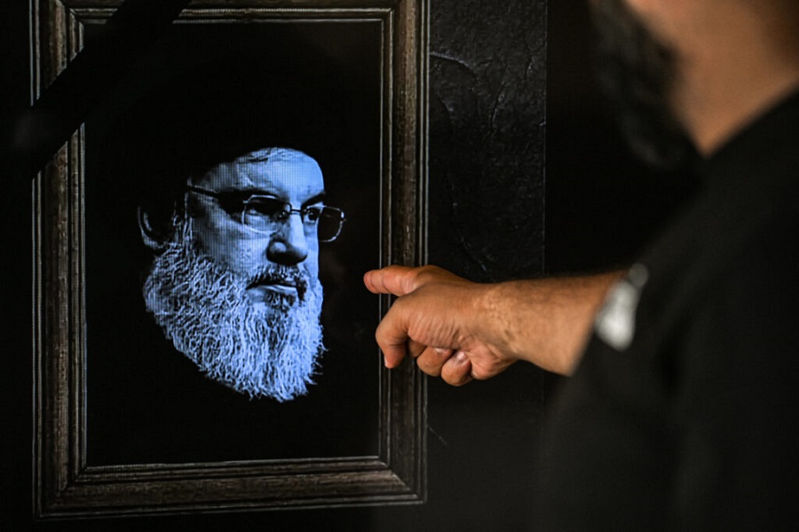 A man points to a television set displaying an image of the late leader of Hezbollah Hassan Nasrallah with a black stripe for mourning during a broadcast from the private Lebanese station NBN in Beirut on September 28, 2024. Lebanon's Iran-backed Hezbollah group confirmed on September 28, 2024 that its leader Hassan Nasrallah had been killed, after Israel said it had "eliminated" him in a strike on south Beirut a day earlier. (Photo by JOSEPH EID / AFP)