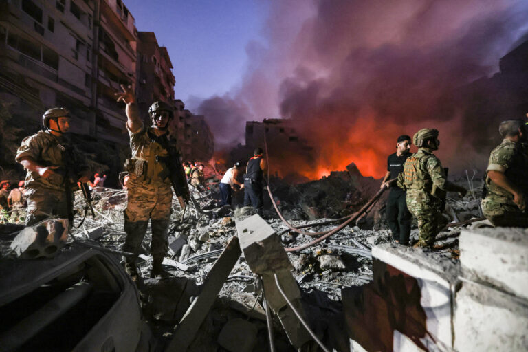 Lebanese army soldiers gather over the rubble of a levelled buildings as people flight the flames, following Israeli air strikes in the Haret Hreik neighbourhood of Beirut's southern suburbs on September 27, 2024. A source close to Hezbollah said the massive Israeli strikes on Beirut's southern suburbs flattened six buildings. (Photo by Ibrahim AMRO / AFP)