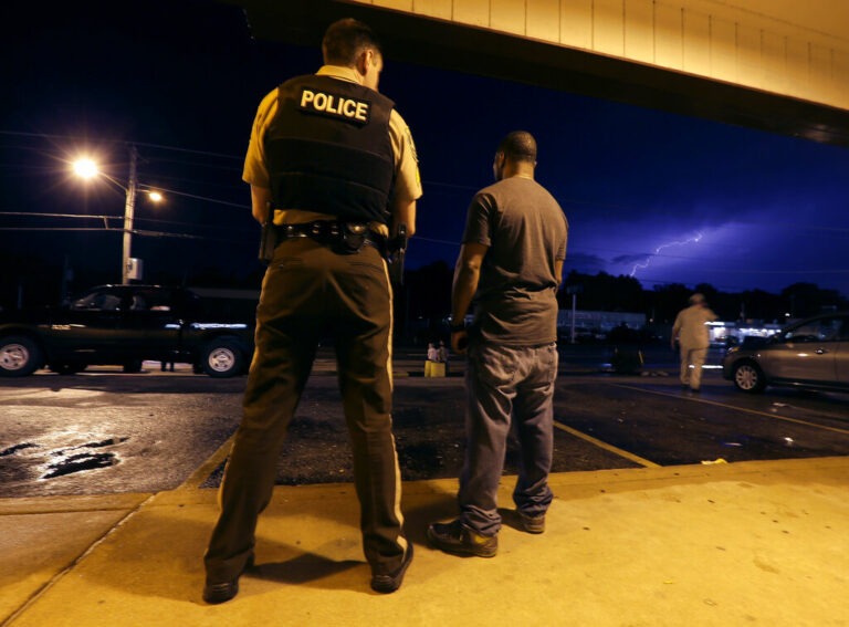 St. Louis County Police Sgt. Colby Dolly and Charles Mayo talk while waiting out a thunderstorm during a protest of the shooting of Michael Brown Wednesday, Aug. 20, 2014, in Ferguson, Mo. Brown's shooting in the middle of a street Aug 9, by a Ferguson policeman has sparked more than week of protests, riots and looting in the St. Louis suburb. (AP Photo/Charlie Riedel)