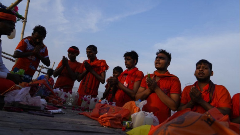 Indian Hindu Kanwarias, worshippers of Hindu God Shiva, offer prayers after taking holy dips in the Ganges River, in Prayagraj, in the northern Indian state of Uttar Pradesh, Saturday, July 23, 2022. Kanwarias are devotees performing a ritual pilgrimage in which they walk the roads of India, clad in saffron, and carrying ornately decorated canisters of sacred water from the Ganges River over their shoulders to take it back to Hindu temples in their hometowns, during the Hindu lunar month of Shravana. (AP Photo/Rajesh Kumar Singh)