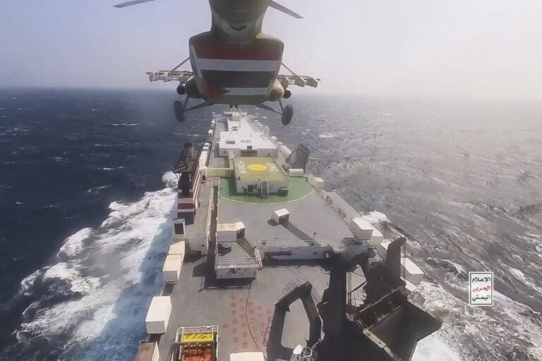 This photo released by the Houthi Media Center shows a Houthi forces helicopter approaching the cargo ship Galaxy Leader on Sunday, Nov. 19, 2023. Yemen's Houthis have seized the ship in the Red Sea off the coast of Yemen after threatening to seize all vessels owned by Israeli companies. (Houthi Media Center via AP)