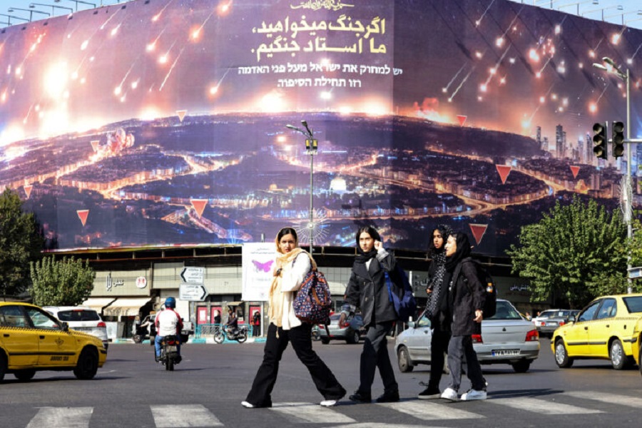 Women walk past an anti-Israel billboard covering the facade of a building in Tehran on October 26, 2024. Residents of Tehran awoke and went about their business as planned on October 26 after their sleep was troubled by Israeli strikes that triggered blasts that echoed across the city. (Photo by ATTA KENARE / AFP)