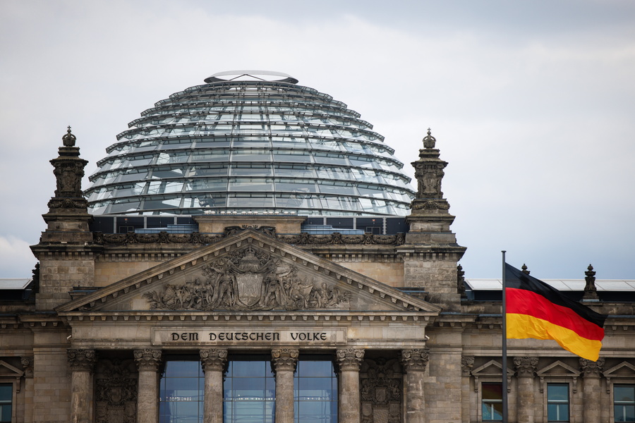 epa11295937 The German national flag flies in front of the Reichstag building, the seat of the German parliament Bundestag, in Berlin, Germany, 23 April 2024. The German Federal Constitutional Court in Karlsruhe is hearing a complaint against a reform bill of the electoral law that would reduce the number of MPs in the Bundestag.  EPA/CLEMENS BILAN