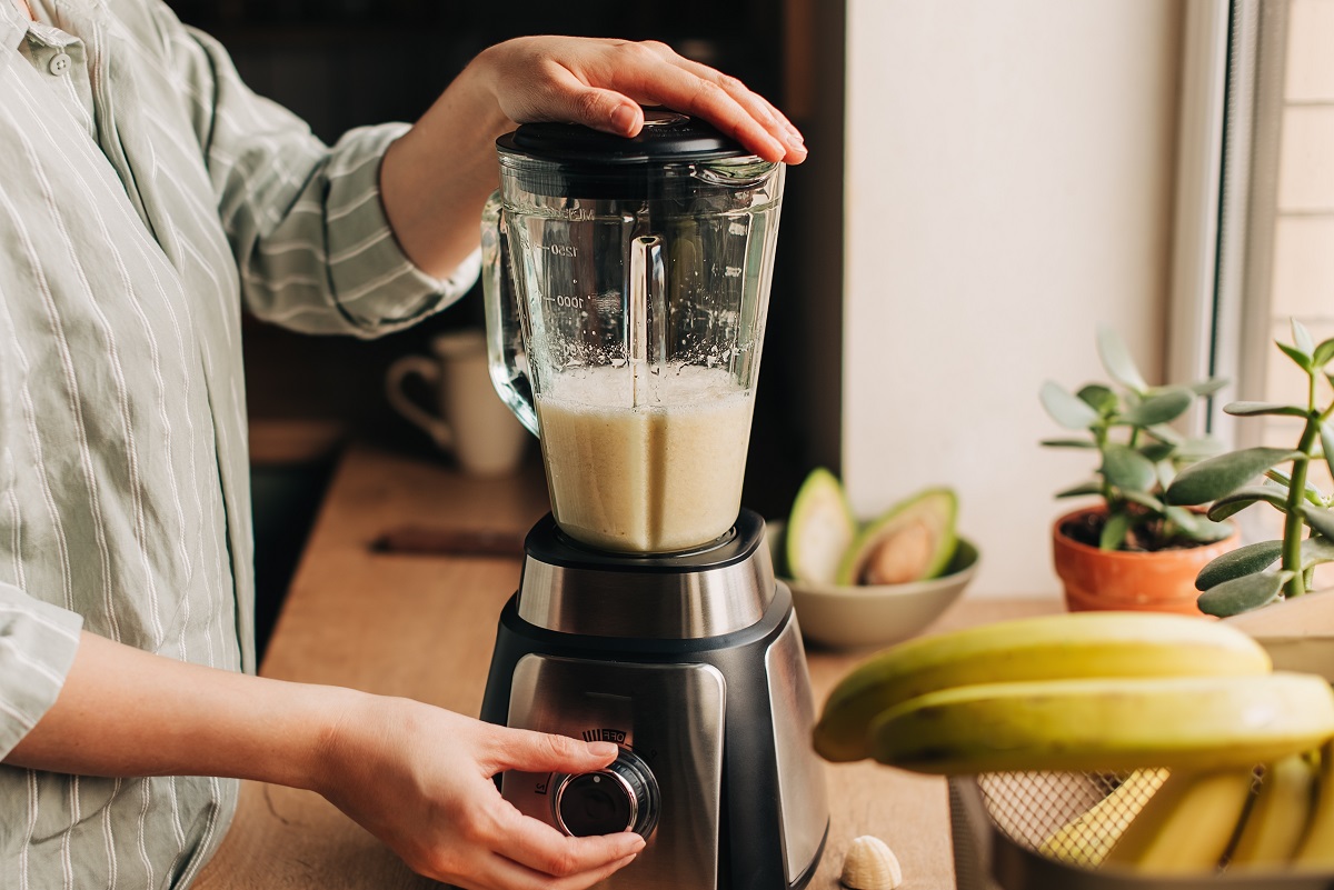 Woman,Blending,Spinach,,Berries,,Bananas,And,Almond,Milk,To,Make