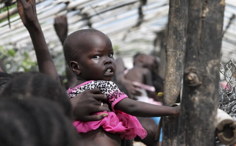 In this photo taken Monday, July 25, 2016, a baby is lifted up as people queue for food distribution in a camp for the displaced at the United Nations base in Juba, South Sudan. When South Sudan's president signed a peace deal a year ago to end the country's civil war he added 16 reservations to the agreement, which have now become a map of how it has unraveled. (AP Photo/Justin Lynch)