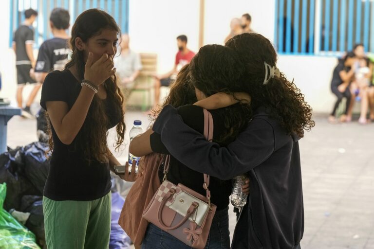 Displaced youth hug as they take shelter at a school in Beirut, after fleeing the Israeli airstrikes in the south with their families, Thursday, Sept. 26, 2024. (AP Photo/Bilal Hussein)