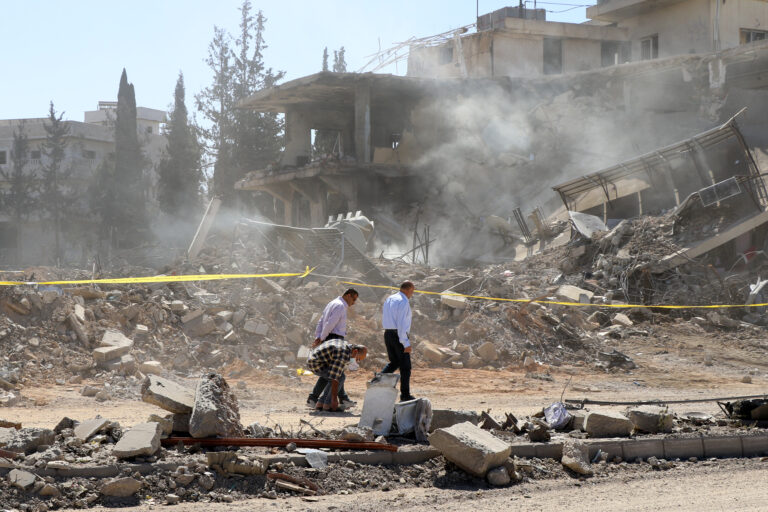 Men walk past a destroyed building following an Israeli air strike in the village of Douris southeast of Baalbek in Lebanon's eastern Bekaa Valley on October 15, 2024. Israel expanded operations in Lebanon nearly a year after Hezbollah began exchanging fire in support of its ally, Hamas, following the Palestinian group's deadly attack on Israel on October 7, 2023. (Photo by Nidal SOLH / AFP)