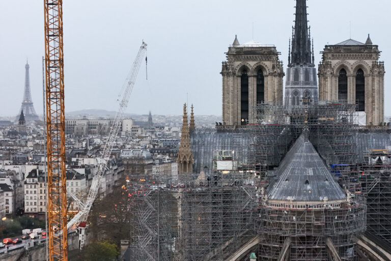 This aerial photograph shows scaffoldings on Notre-Dame de Paris cathedral with the Eiffel Tower in the background a few days before its reopening, on November 25, 2024. The Notre-Dame Cathedral is set to re-open early December 2024, with a planned weekend of ceremonies on December 7 and 8, 2024, five years after the 2019 fire which ravaged the world heritage landmark and toppled its spire. Some 250 companies and hundreds of experts were mobilised for the five-year restoration costing hundreds of millions of euros. (Photo by Damien MEYER / AFP)